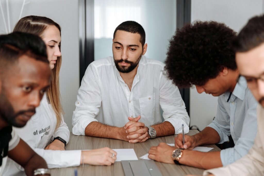 A diverse team of adults collaborating in an office meeting, showcasing teamwork and professionalism.