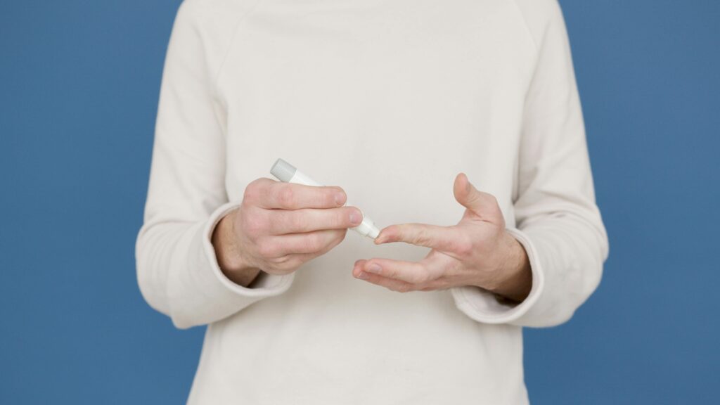 Adult using insulin pen for blood sugar monitoring against blue background.