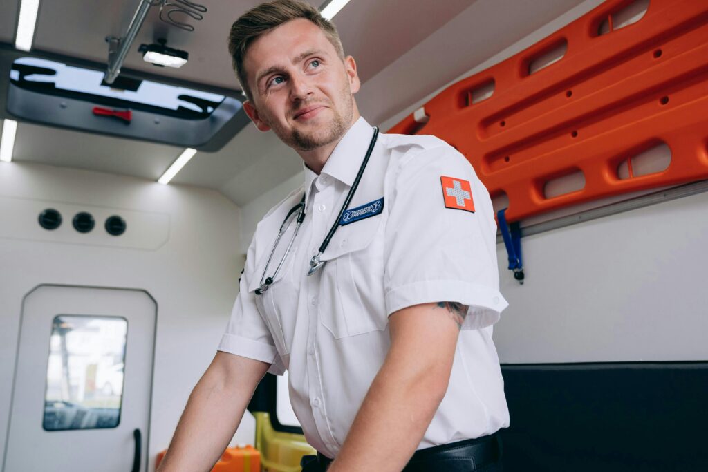 Paramedic posing confidently inside an ambulance, showcasing emergency medical equipment.