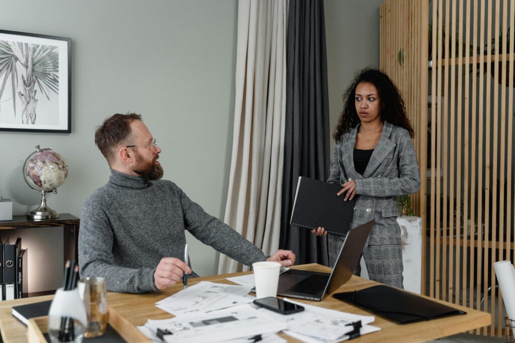 Two colleagues engaged in discussion with documents in a modern office setting.