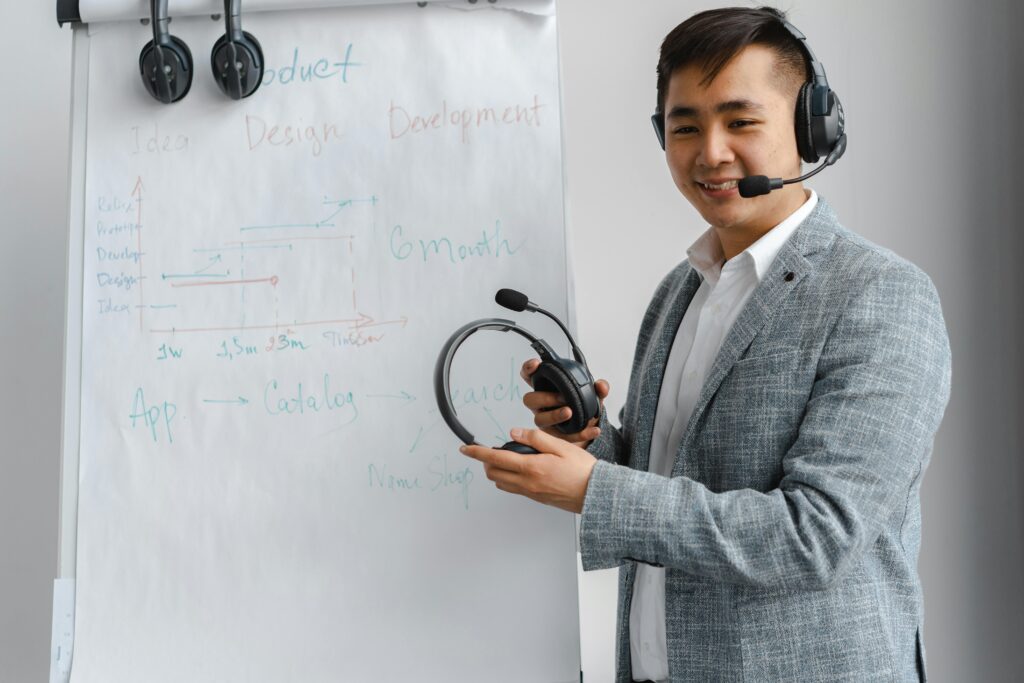 Asian man explaining a concept in a training session with a headset and flip chart.