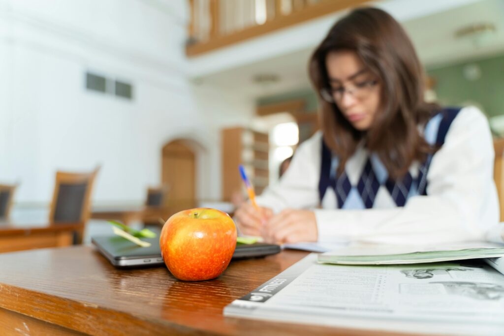 Student studying with notes and an apple on a desk, symbolizing education and focus.