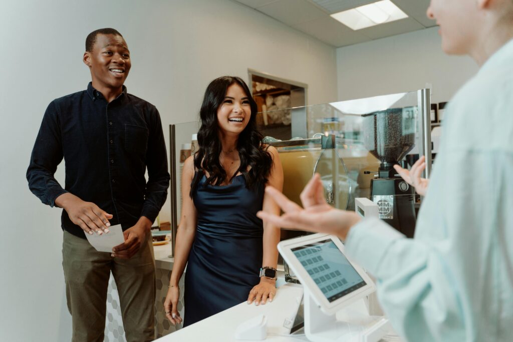 Smiling group at a coffee shop counter, engaging with a cashier, creating a warm atmosphere.